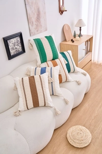 Close-up of geometric striped pillowcases with handmade tassels and textured embroidery