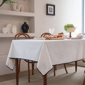 Minimalist white tablecloth with decorative black wave edges on a wooden table