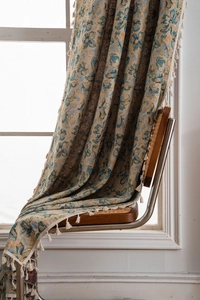 Detailed view of floral jacquard curtain fabric with decorative cream tassels and fringe