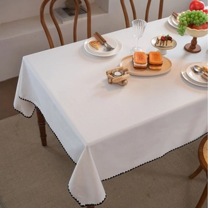 White tablecloth with elegant black scalloped edges on a wooden rectangular table