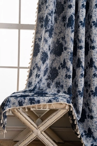 Detailed view of navy floral jacquard curtain fabric with decorative beige tassel edges