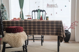 Détail de la nappe épaisse à carreaux marron avec décor festif et coussins doux