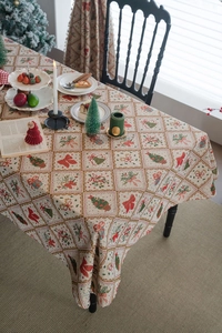 Detail of Christmas jacquard tablecloth with bow and gift patterns on a festive wooden table
