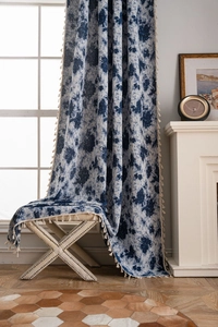 Detail of blue floral curtain with beige tassel trim and rustic linen texture