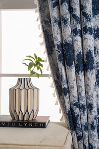 Detail of blue and beige jacquard curtains featuring vintage floral patterns and white tassels
