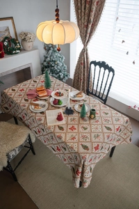 Detail of Christmas jacquard tablecloth featuring festive bows and green pine tree patterns