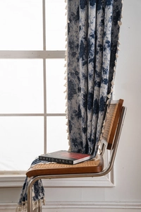 Close-up of blue geometric jacquard fabric curtain with decorative cream tassels