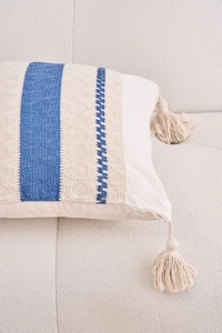 Detail of bohemian cream pillow cover with blue geometric weave and soft cotton tassels
