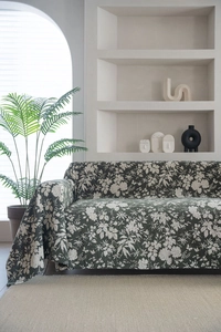 Close-up of dark green floral sofa cover with white blossom patterns in a modern room