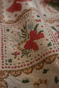 Close-up of jacquard fabric with festive red floral motifs and shiny gold silk threads