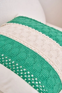 Close-up of green and white knit pillow cover showing intricate hollow-out texture