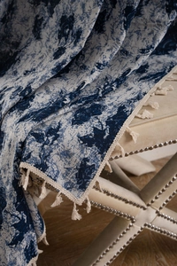 Close-up of blue floral jacquard fabric texture with elegant beige tassel fringe edges