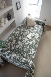 Detailed fabric texture of dark green floral sofa cover in a modern living room setting