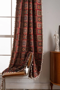 Detail of red geometric jacquard curtain fabric with ethnic pattern and white tassels