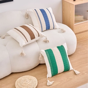 Bohemian geometric striped square throw pillow covers with decorative tassels on cream sofa