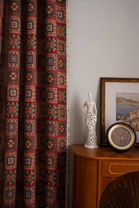 Detail view of red bohemian curtains featuring geometric patterns and ivory tassel trim