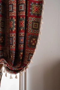 Close-up of red geometric bohemian jacquard fabric with detailed white tassel trim