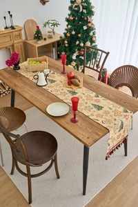 Detail eines Weihnachts-Tischläufers mit Lebkuchenmann-Motiven und festlichen Pompon-Fransen