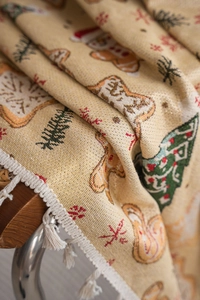 Close-up of beige Christmas jacquard fabric with gingerbread man and white tassels