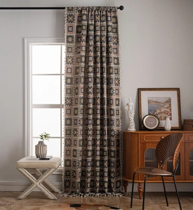 Detailed view of geometric jacquard curtain fabric with decorative cream tassels at the edge
