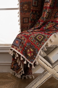 Detail of bohemian red jacquard knit throw with geometric ethnic pattern and soft tassels