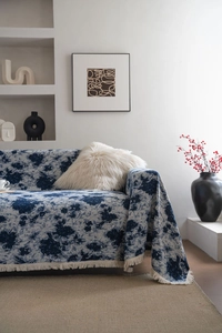 Detailed close-up of blue floral jacquard sofa throw with decorative fringe edges