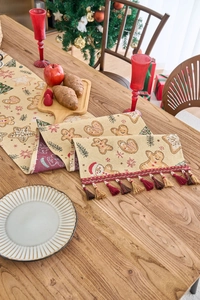 Detail eines Weihnachts-Tischläufers mit Lebkuchenmann-Mustern und bunten Quasten