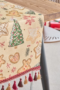 Detail eines Weihnachts-Tischläufers mit Lebkuchenmann-Jacquard und goldenen Quasten