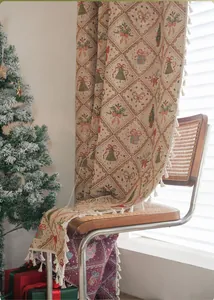 Close-up of beige Christmas throw with red bow patterns and white fringe tassels