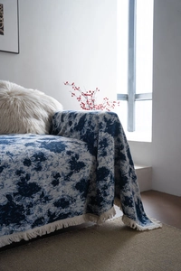 Detail of blue and beige floral jacquard sofa throw with thick knit texture and fringe