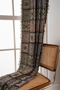Detailed view of geometric jacquard throw blanket with cream fringes on a rattan chair