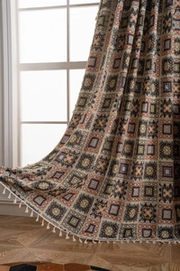 Detail showing jacquard geometric pattern curtains with white tassel fringe in cozy room