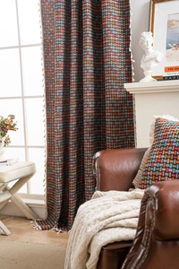 Gros plan sur les rideaux jacquard géométriques et coussins assortis à franges beige