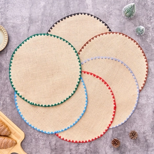 Detail of round jute placemats with colorful embroidered triangle edges on stone surface