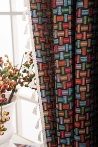 Gros plan sur un tissu jacquard géométrique coloré avec des franges à pompons blancs bohèmes