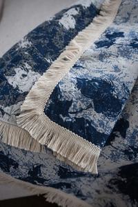 Detailed blue jacquard knit throw blanket texture with delicate cream fringe tassels
