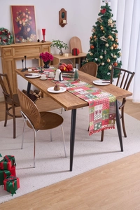Close-up of Christmas table runner with reindeer pattern and festive red pom-poms