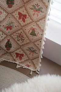 Close-up of Christmas jacquard fabric with festive bows and soft cotton fringe detail