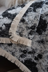 Détail du tissu jacquard épais avec motif floral noir graffiti et bordure à franges ivoire