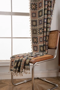 Detail of bohemian geometric jacquard knit throw blanket with white tassel fringe edges
