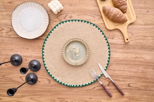 Macro shot of circular woven placemat with natural texture and green scalloped edges