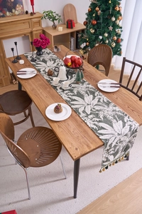 Dettaglio del runner da tavolo verde scuro con foglie di palma e nappe fatte a mano
