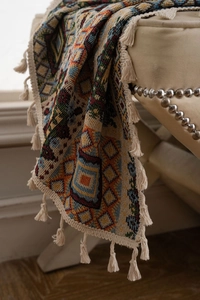 Close-up of geometric woven throw blanket with colorful bohemian patterns and white tassels