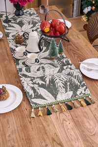 Dettaglio del runner da tavolo con foglie di palma e nappe colorate in stile boho