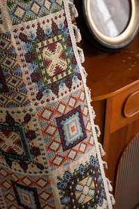 Detail showing jacquard texture and beige cotton tassels of retro geometric curtain