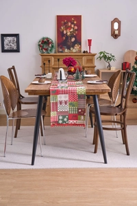 Detailed patchwork Christmas table runner with festive elk patterns and red pompom trim