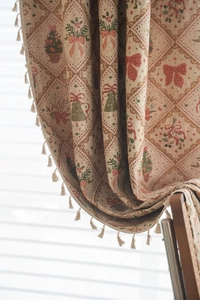 Detailed fabric texture of Christmas curtain with red bows and beige ball tassel trim