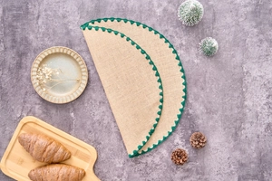 Detail of round natural jute placemats with green crochet lace edge on a rustic grey surface