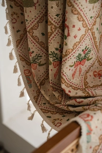 Close-up of festive jacquard curtain with red bows, green leaves and fringe detail