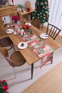 Close-up of Christmas table runner with reindeer patterns and red pompom fringe detail